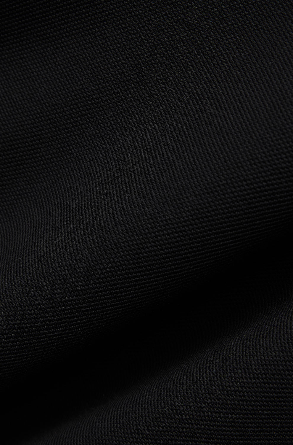 Gros plan du tissu noir texturé du polo, avec surface en tricot fin et plis souples pour homme par Psycho Bunny