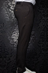 Pantalon brun foncé vu de côté, avec poche passepoilée arrière boutonnée et écusson à la taille pour homme par Au Noir