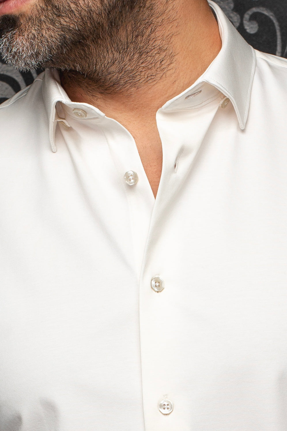 Gros plan du col d'une chemise blanche avec boutons nacrés et tissu lisse pour homme par Au Noir
