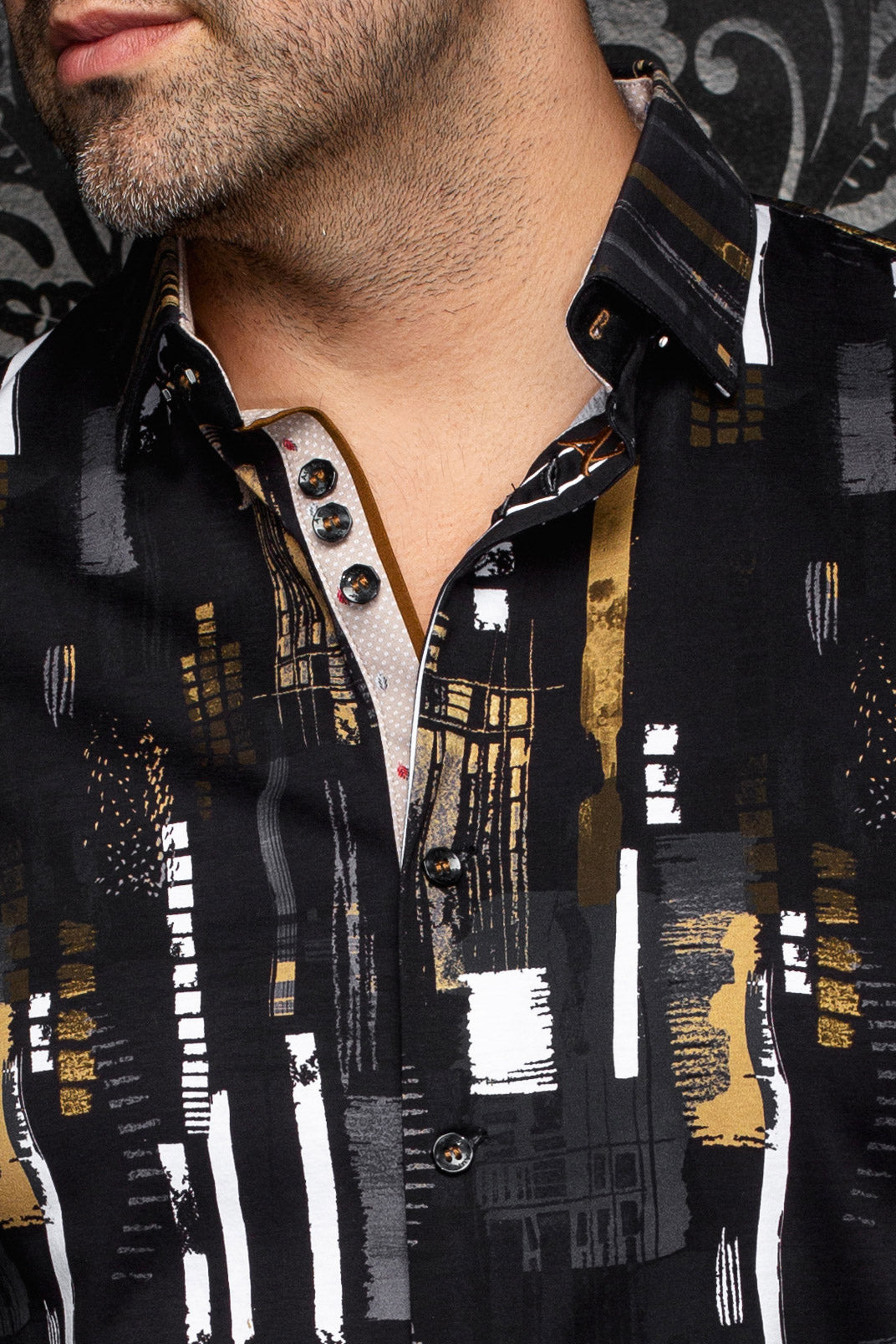 Détail du col d’une chemise noire imprimée avec patte beige, boutons foncés et accents blancs pour homme par Au Noir