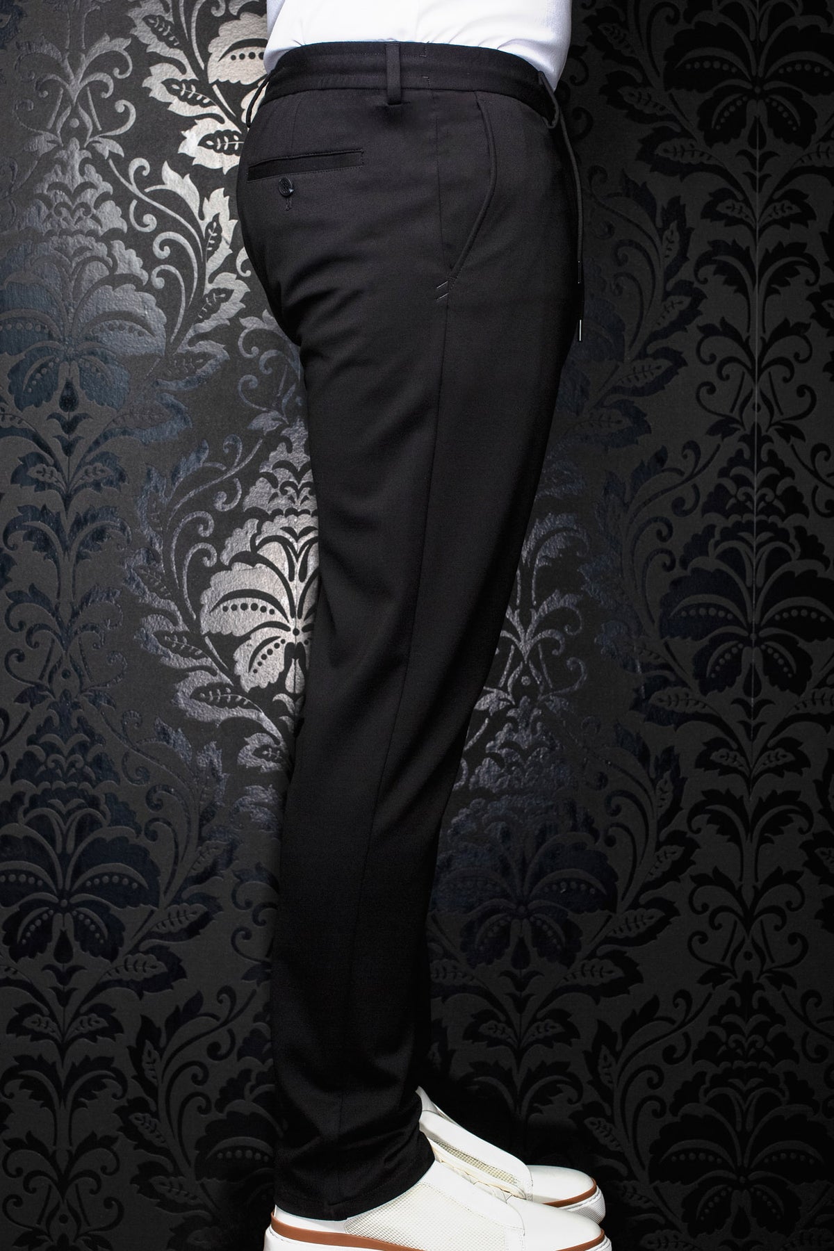 Pantalon noir vu de côté, avec passants, poche arrière passepoilée boutonnée et jambe fuselée pour homme par Au Noir