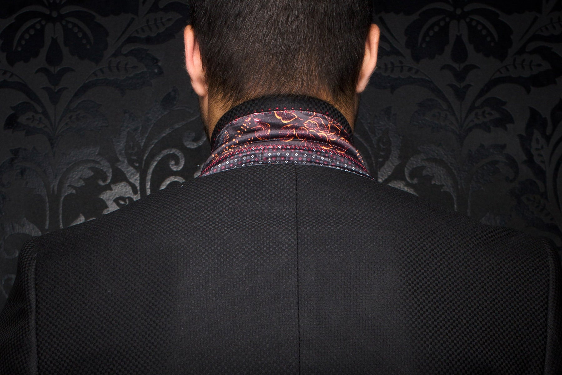 Gros plan dos d’un veston noir texturé avec doublure de col à motif et couture centrale pour homme par Au Noir