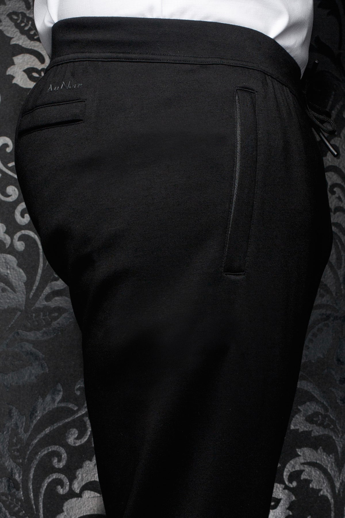Pantalon jogging noir avec taille large, poche passepoilée et logo ton sur ton pour homme par Au Noir, en gros plan