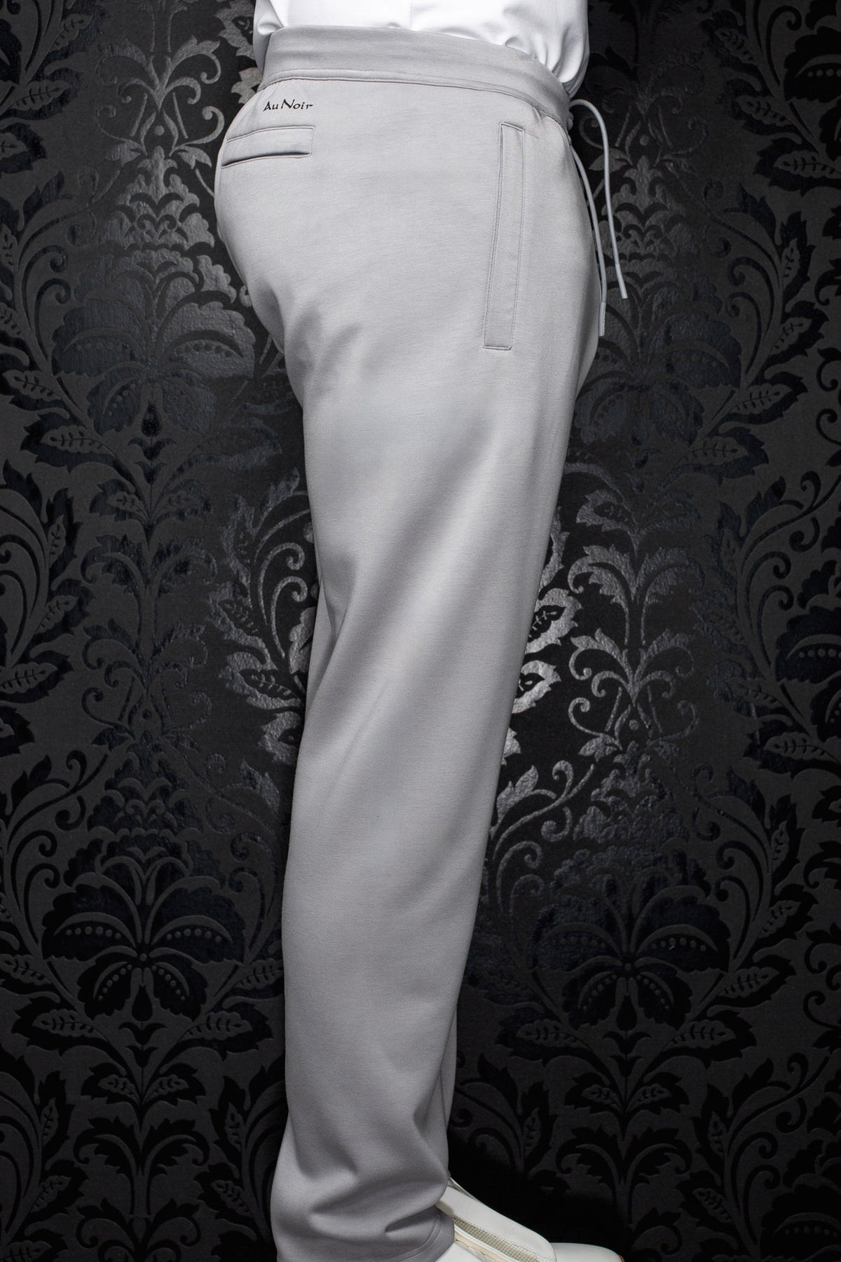 Pantalon jogging gris pâle vu de côté avec taille élastique, cordon et poches passepoilées pour homme par Au Noir