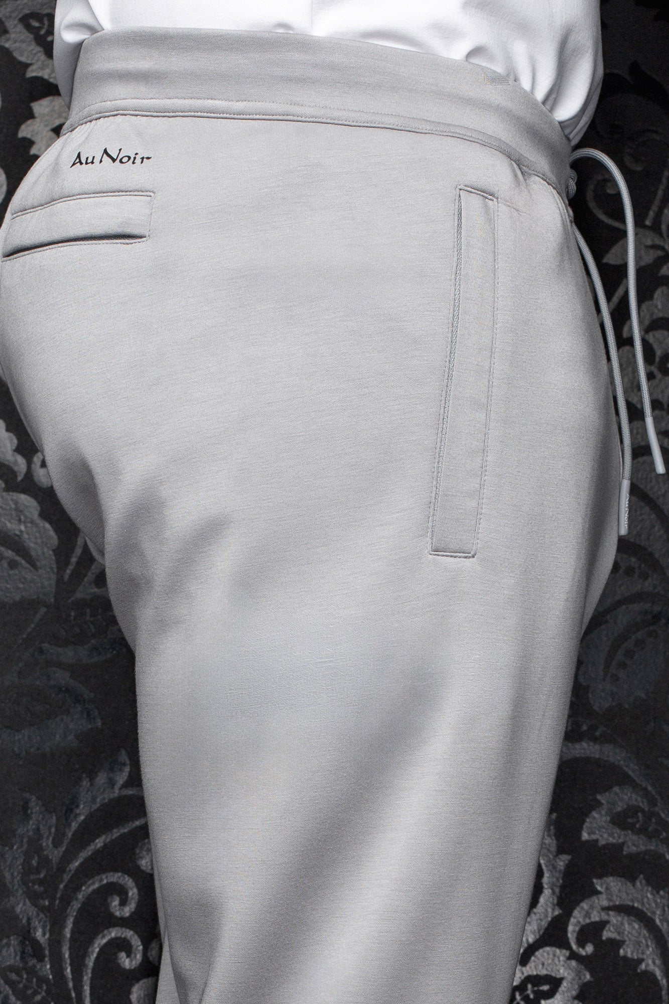 Pantalon jogging gris pâle avec taille à cordon, poches passepoilées et logo Au Noir noir pour homme, en gros plan