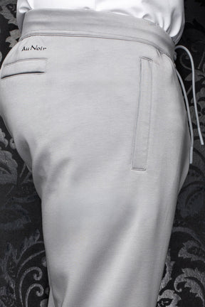 Pantalon jogging gris pâle avec taille à cordon, poches passepoilées et logo Au Noir noir pour homme, en gros plan