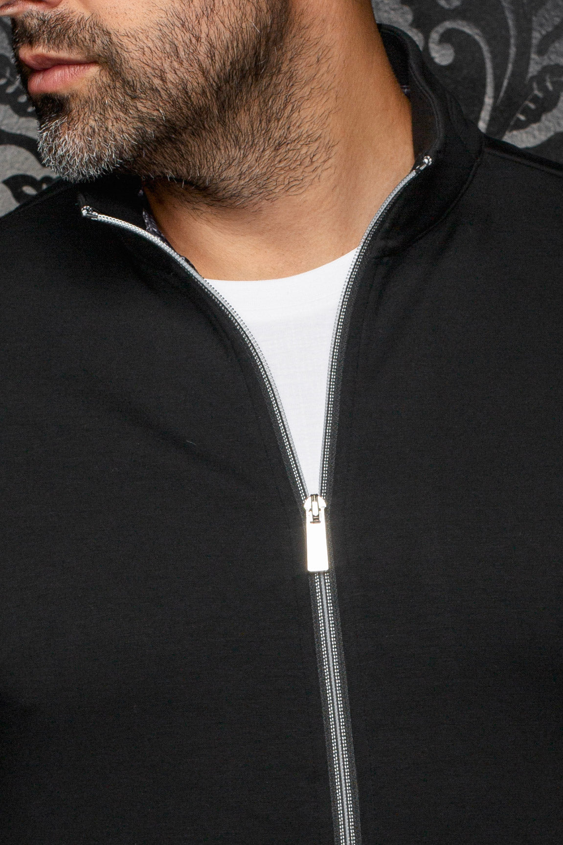 Col montant noir et fermeture argentée entrouverte sur une veste sport blanc pour homme par Au Noir, en gros plan