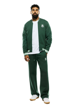 Psycho Bunny men's dark green wide-leg sweatpants with thigh logo patch and drawstring waist shown from the front