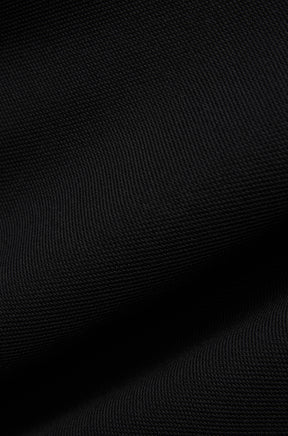 Psycho Bunny men's black textured polo fabric showing the fine knit surface and soft folds, close-up