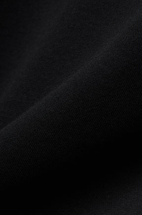 Psycho Bunny men's close-up detail of black knit sweatshirt fabric showing a smooth textured surface