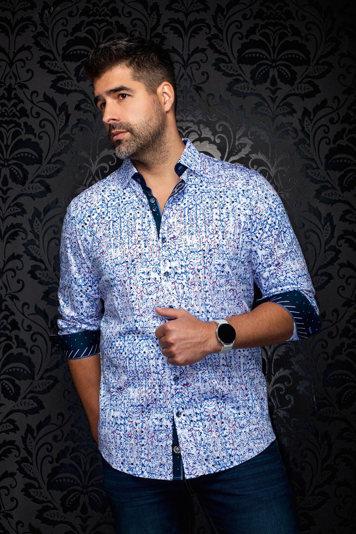 Vue en angle d’une chemise blanche florale à motif bleu et rouge avec poignets marine roulés pour homme par Au Noir