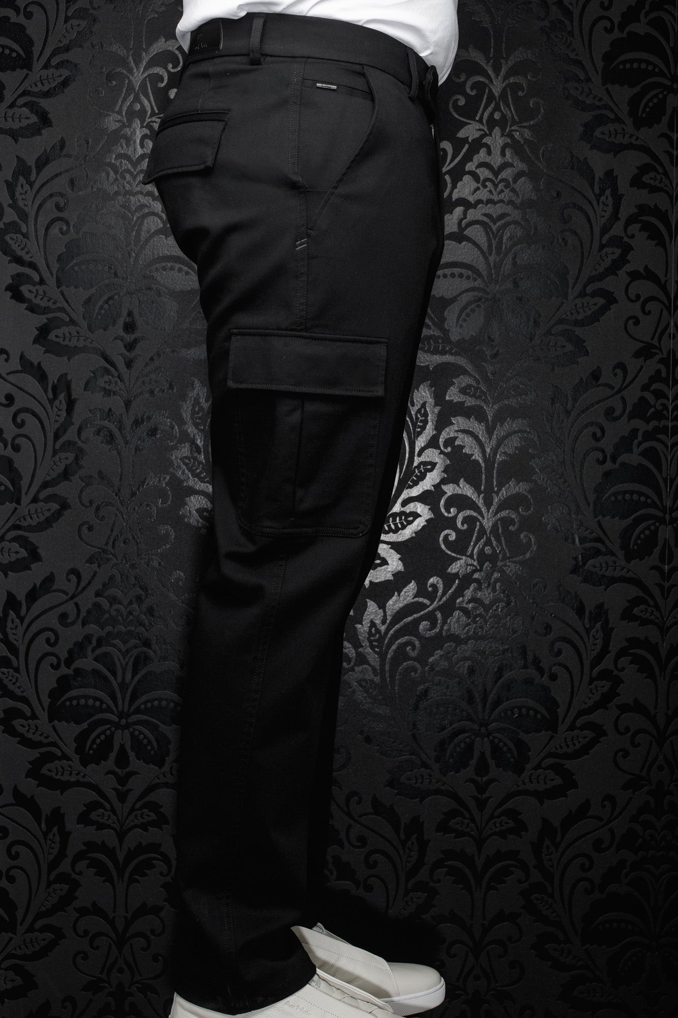 Pantalon cargo noir avec poche à rabat, passants et petite étiquette métal pour homme par Au Noir, vue de côté