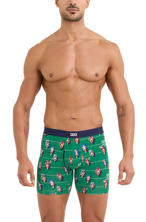 Front model view of men's green football-print boxer briefs with navy SAXX waistband
